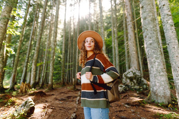 Young woman with backpack walking in beautiful  forest. Hiking and leisure theme.