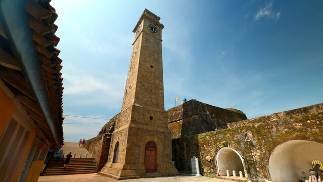 Ancient clock tower in fortress. Action. Beautiful sunny view of stone walls and clock tower in ancient fortress. Ancient fortress with clock tower on sunny summer day