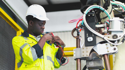 Fototapeta premium An African professional engineering is fixing or testing the arm of robotic that use in the factory or industry working, concept of futuristic manufacturing, innovation intelligence, invention success