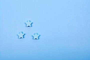 Three blue wooden stars shapes symbol label form isolated on the bright solid fond plain bright...