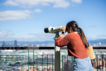 Fototapeta na wymiar Tourist woman look at the binocular in the city