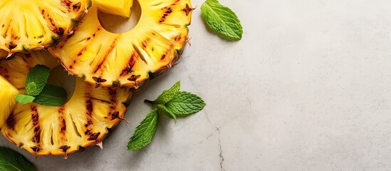 Closeup of delicious grilled pineapple slices topped with fresh mint leaves on a light gray marble surface. - Powered by Adobe