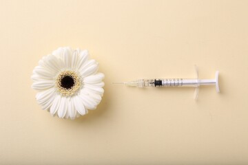 Cosmetology. Medical syringe and gerbera flower on yellow background, flat lay