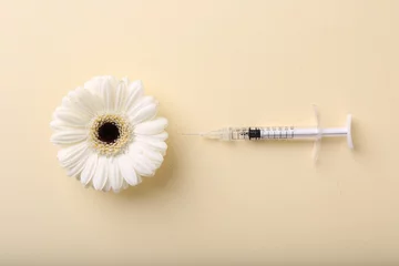 Foto op Plexiglas Cosmetology. Medical syringe and gerbera flower on yellow background, flat lay © New Africa