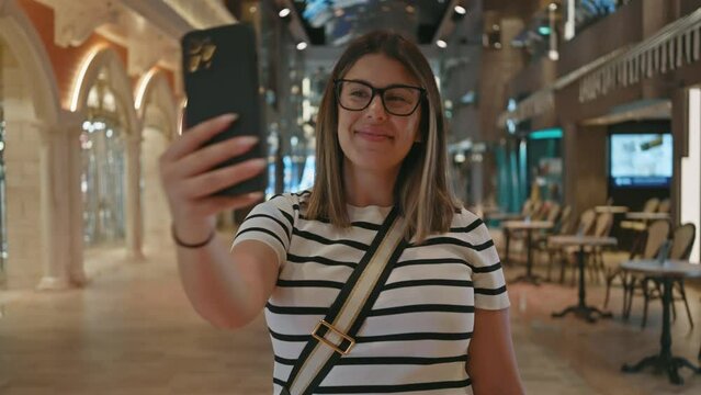 A young woman takes a selfie inside a luxurious cruise ship, embodying modern travel and vacation vibes.