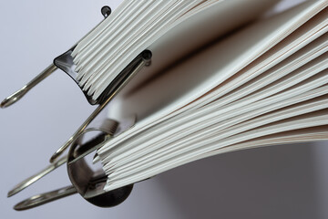 close-up of paper signatures (bookbinding) held together with spring clips arranged standing