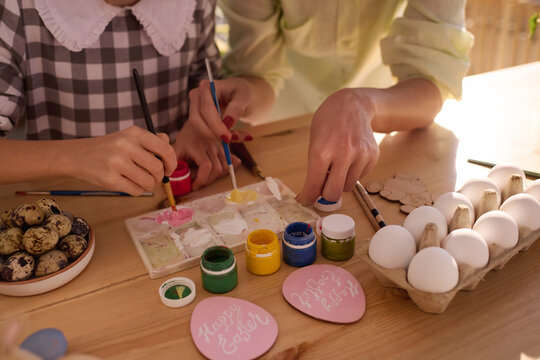 High angle view closeup shot of unrecognizable woman and her daughter mixing paints to decorate eggs for Easter