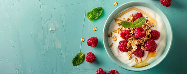 Greek yogurt with granola, honey and raspberries on light green background Top view space to copy.