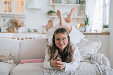 Cheerful girl lying on couch, playful pose in a cozy living room, relaxed and happy at home