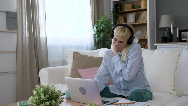Young businesswoman freelancer global business expert working at home in home office on laptop computer having problems with shoulders and neck pain from sitting long time. Uncomfortable position