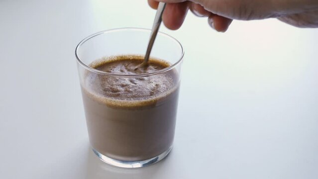 Male hand mixing with scoop of chocolate whey protein powder into a healthy shake for energy for training in a home kitchen. .Boy with nutritional sports supplement for musc.