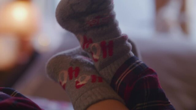 The girl lies on the bed dangling her legs against the background of the window