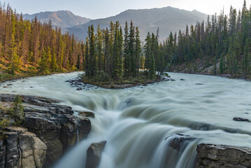Sunwapta Falls in the stunning Canadian Rockies at sunrise in summertime with beautiful cascading...