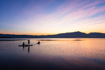 Silhouette of 3 people enjoy punting in  the lake at sun set