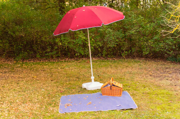 Empty picnic area with red lampshade, blanket and picnic basket