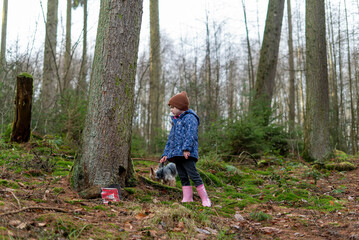 Little girl walking with her dog in the forest. Happy childhood.