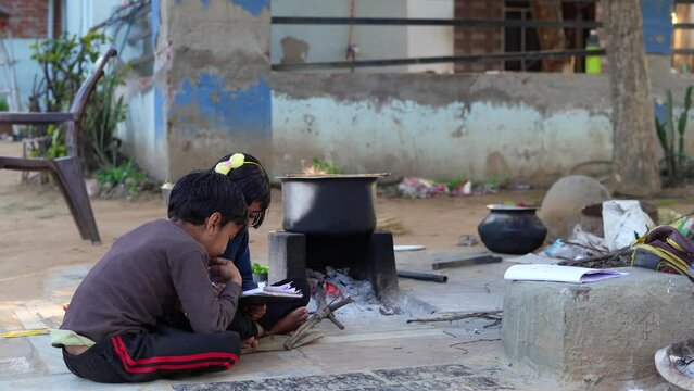 Elementary school students girl and boy doing homework outdoor. Village kids reading book and writing with pencil. Poor children education learning studying together