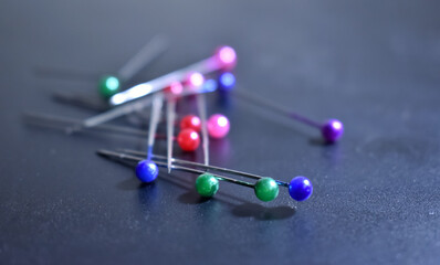 A closeup picture of colourful ball pins spread over a black.