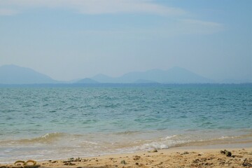 Fototapeta premium Sea, beautiful sandy beach slight wave Contrast the horizon line with mountains and sky.