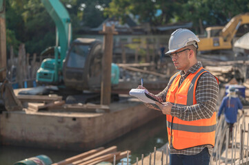 Construction engineer working on a bridge construction site over a river,Civil engineer supervising...