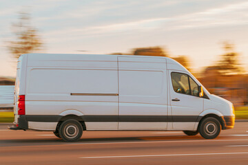 A white cargo van drives down the street at sunset. Commercial transport, small cargo transportation, delivery of goods. Motion blur