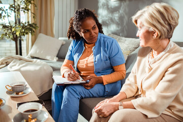 Senior woman talking to caregiver at home