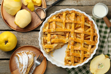 Tasty homemade quince pie, ingredients, peeler and fork on wooden table, flat lay
