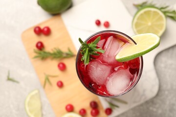 Tasty cranberry cocktail with rosemary and lime in glass on table, top view