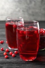 Tasty cranberry juice in glasses and fresh berries on black wooden table, closeup