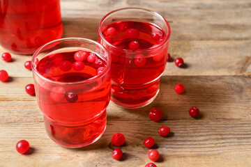 Tasty cranberry juice in glasses and fresh berries on wooden table, closeup
