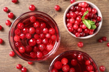 Tasty cranberry juice in glasses and fresh berries on wooden table, flat lay