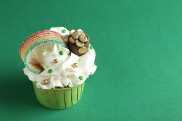 St. Patrick's day party. Tasty cupcake with sour rainbow belt and pot of gold toppers on green...