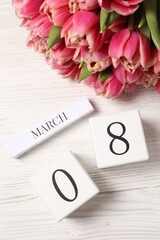 International Women's day - 8th of March. Block calendar and bouquet of beautiful tulips on white wooden table, flat lay