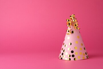 One beautiful party hat with serpentine streamers on pink background. Space for text