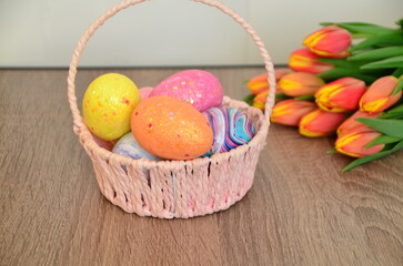 Easter, Easter egg color vibrant, spring Orthodox holiday. colorful decorated eggs in a pink basket. inscription happy easter, gift, red yellow tulips