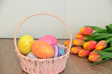 Easter, Easter egg color vibrant, spring Orthodox holiday. colorful decorated eggs in a pink basket. inscription happy easter, gift, red yellow tulips