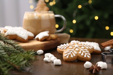 Fototapeta na wymiar Decorated cookies on table against blurred Christmas lights, closeup