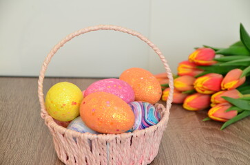 Easter, Easter egg color vibrant, spring Orthodox holiday. colorful decorated eggs in a pink basket. inscription happy easter, gift, red yellow tulips