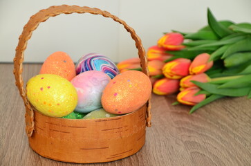 Easter, Easter egg color vibrant, spring Orthodox holiday. colorful decorated eggs in a pink basket. inscription happy easter, gift, red yellow tulips