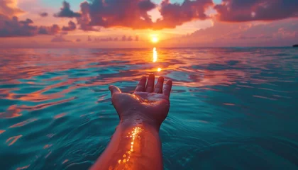 Crédence de cuisine en verre imprimé Coucher de soleil sur la plage female hand over the calm ocean at sunset