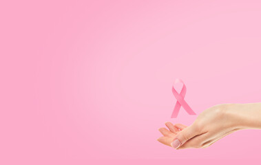 Pink Breast Cancer Awareness Ribbon. Female hand holding pink ribbon flying symbol of fight against...