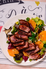 Fried duck breast in honey soy glaze with mixed salad and oranges.top veiw.