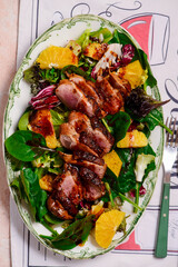 Fried duck breast in honey soy glaze with mixed salad and oranges.top veiw.