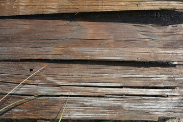 Construction wooden boards with old construction brown paint, green grass and sand after rain.