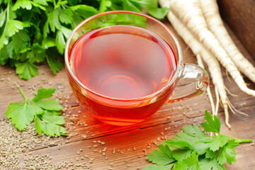 Parsley tea with fresh seeds, leaves, roots nearby on rustic wooden table, copy space, natural remedy for kidney, heart, menstrual, blood desease, healthy organic food concept
