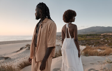 Black couple standing away on sand beach with dry grass plants