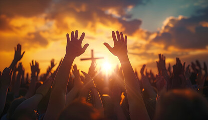 hands raised up to a cross with sunset background