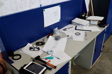 High angle view no people shot of technical drawings, tools, and digital tablet on table in modern factory