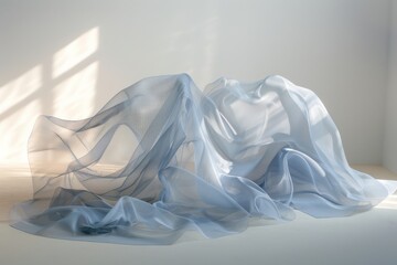 Soft blue fabric drapes create flowing shapes and cast intricate shadows in a serene, minimalist setup