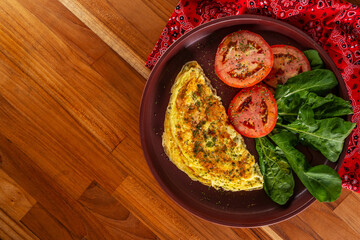 plate with an omelet and salad of sliced tomatoes and arugula